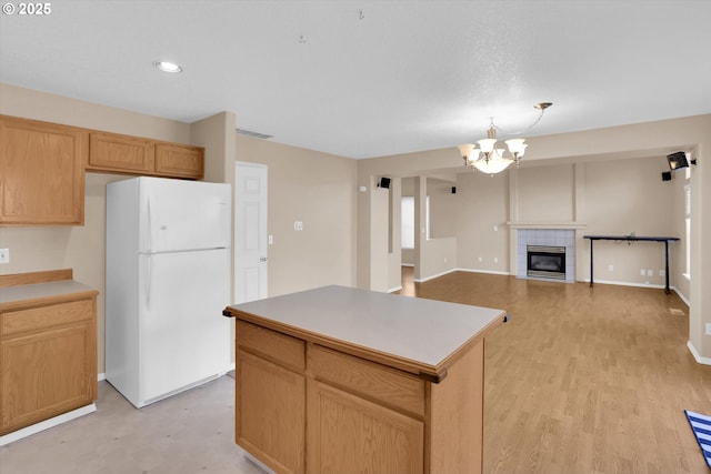 kitchen featuring freestanding refrigerator, a chandelier, a center island, light wood-type flooring, and light countertops