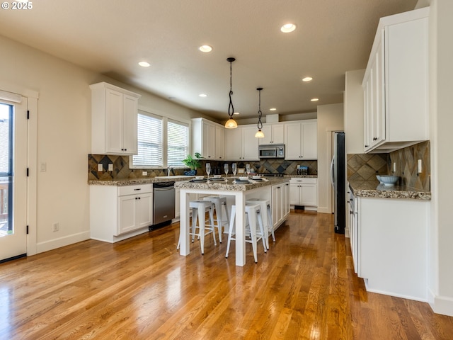 7760 SW Hyland Way, Beaverton, OR 97008 - kitchen with appliances with stainless steel finishes, a center island, a kitchen breakfast bar, tasteful backsplash, and white cabinetry