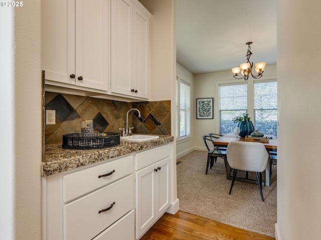 7760 SW Hyland Way, Beaverton, OR 97008 - kitchen featuring a sink, a chandelier, decorative backsplash, white cabinetry, and baseboards