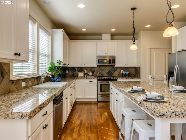 7760 SW Hyland Way, Beaverton, OR 97008 - kitchen featuring stainless steel appliances, a sink, white cabinets, a kitchen bar, and dark wood-type flooring
