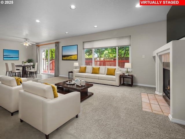 carpeted living room with a tile fireplace and ceiling fan