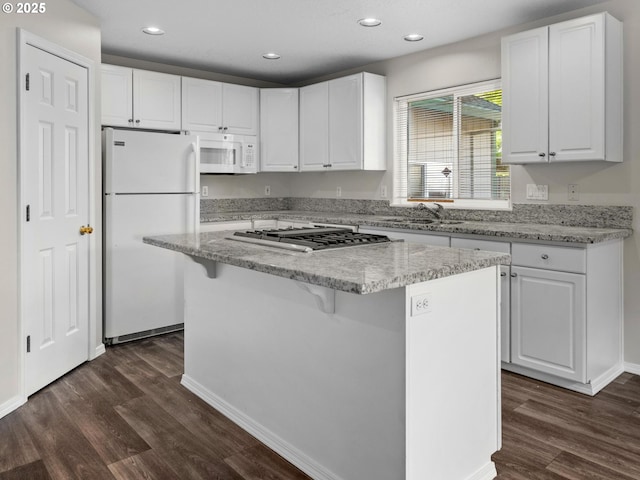 kitchen featuring a kitchen island, white cabinets, and white appliances