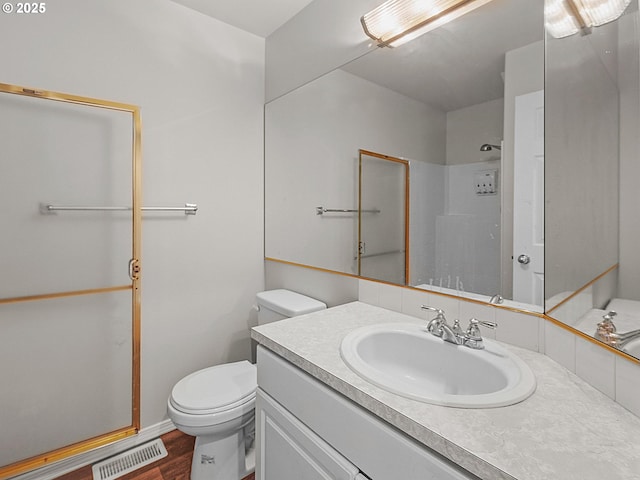 bathroom featuring walk in shower, vanity, toilet, and hardwood / wood-style floors