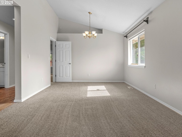 empty room with lofted ceiling, carpet floors, and a chandelier