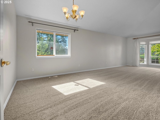 carpeted spare room with an inviting chandelier