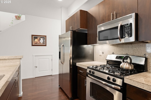 kitchen featuring stainless steel appliances, dark wood-style floors, decorative backsplash, dark brown cabinets, and baseboards