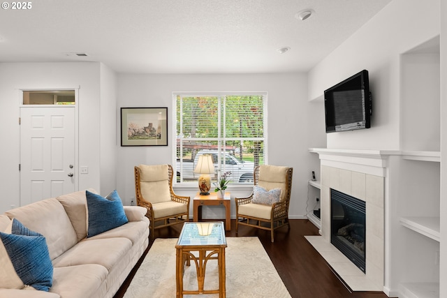 living room with wood finished floors and a tiled fireplace