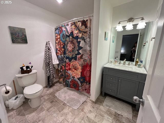 bathroom featuring vanity, stone finish flooring, toilet, and a shower with curtain