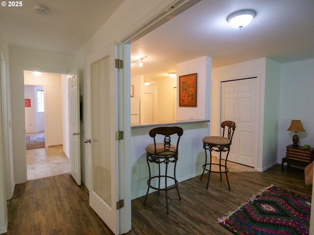 interior space featuring dark wood-type flooring, freestanding refrigerator, baseboards, and a kitchen breakfast bar