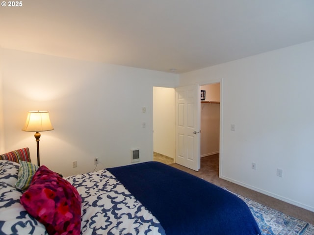 carpeted bedroom with baseboards, visible vents, and a walk in closet