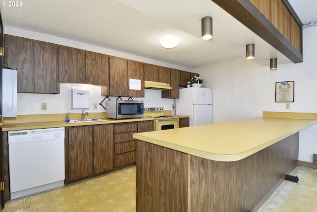 2718 SE 138th Ave Unit 64, Portland, OR 97236 - kitchen with white appliances, light flooring, a peninsula, under cabinet range hood, and a sink