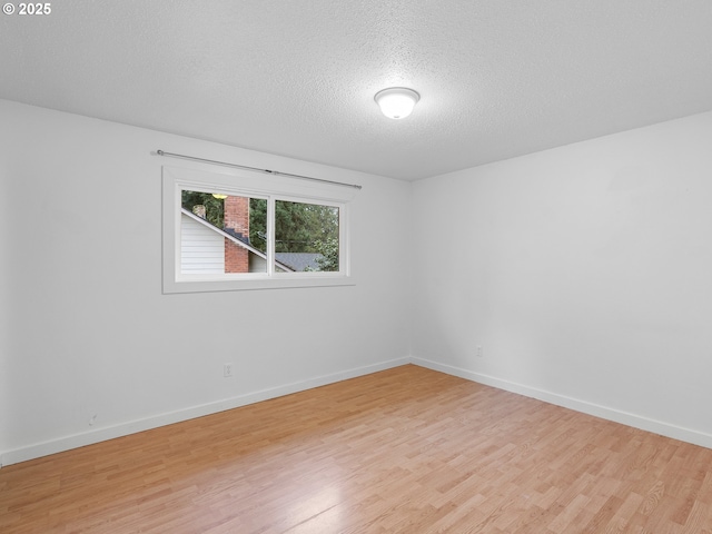 unfurnished room featuring light wood-type flooring and a textured ceiling