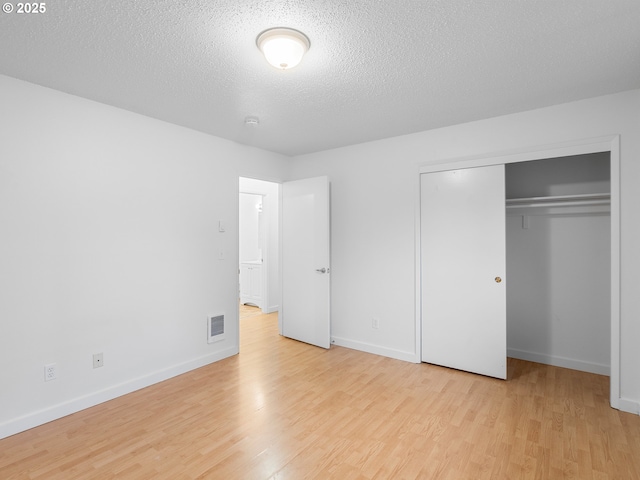 unfurnished bedroom with a closet, a textured ceiling, and light hardwood / wood-style floors