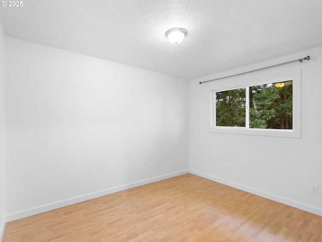 spare room featuring a textured ceiling and light wood-type flooring