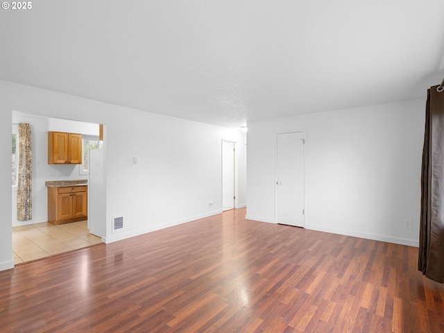 unfurnished room with a textured ceiling and light hardwood / wood-style flooring