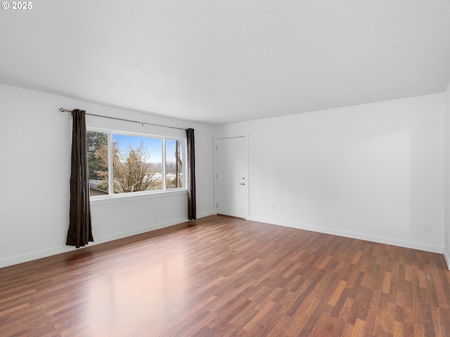 spare room with a textured ceiling and dark wood-type flooring