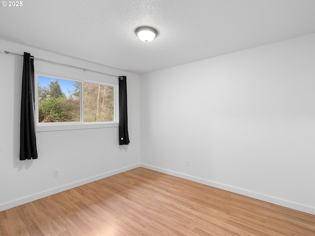 empty room featuring a textured ceiling and light wood-type flooring