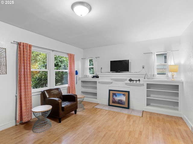 sitting room featuring light wood-type flooring, built in features, and a wealth of natural light