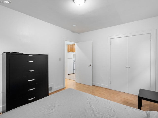 bedroom featuring a closet, light hardwood / wood-style floors, and white fridge