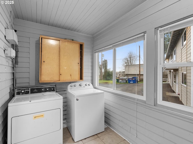 laundry room with separate washer and dryer, a healthy amount of sunlight, wooden walls, and light tile patterned floors