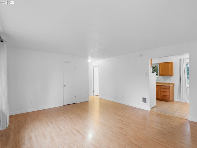 empty room featuring a textured ceiling and light hardwood / wood-style floors