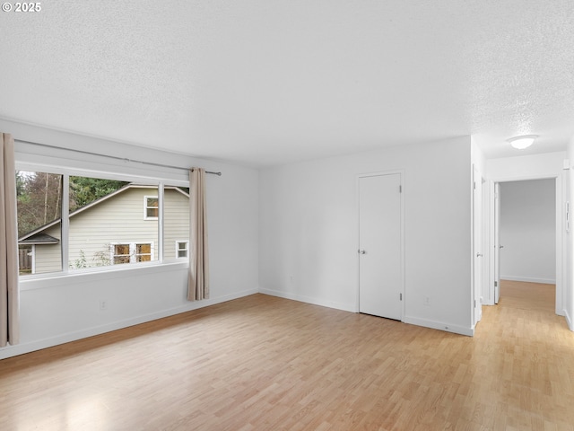 unfurnished room featuring a textured ceiling and light hardwood / wood-style flooring