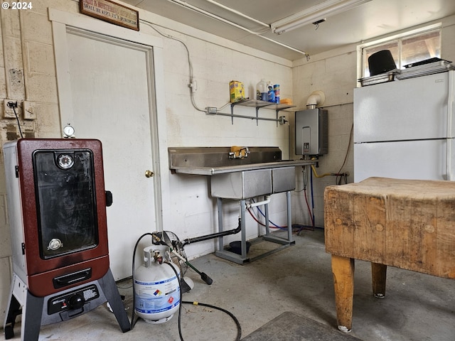 basement featuring water heater, freestanding refrigerator, and concrete block wall