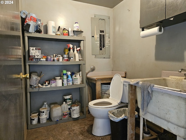 bathroom with toilet, electric panel, and a sink