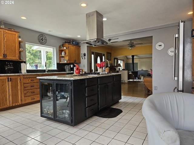 kitchen featuring open floor plan, a wood stove, island exhaust hood, open shelves, and light tile patterned flooring