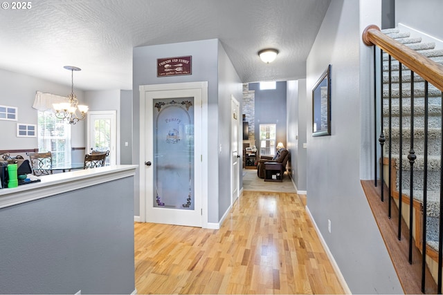 952 S 69th St, Springfield, OR 97478 - foyer entrance featuring light wood-style floors, a chandelier, a textured ceiling, healthy amount of natural light, and stairs