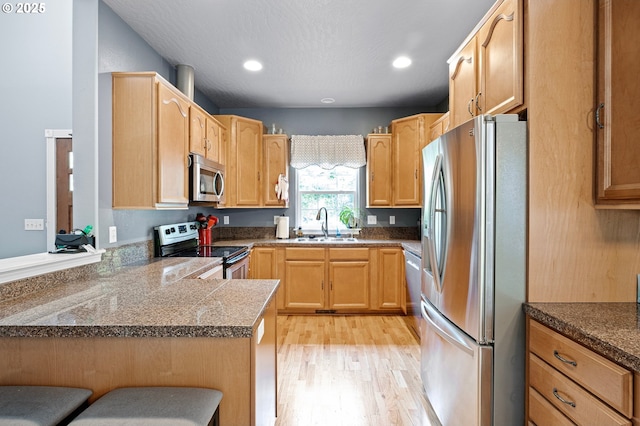 952 S 69th St, Springfield, OR 97478 - kitchen with stainless steel appliances, light wood-style floors, a peninsula, recessed lighting, and a breakfast bar