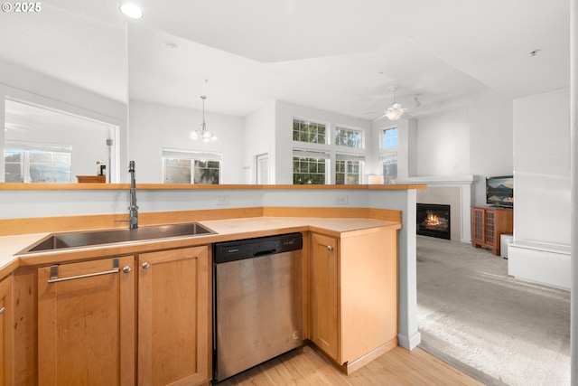 kitchen featuring dishwasher, sink, light carpet, a fireplace, and ceiling fan with notable chandelier