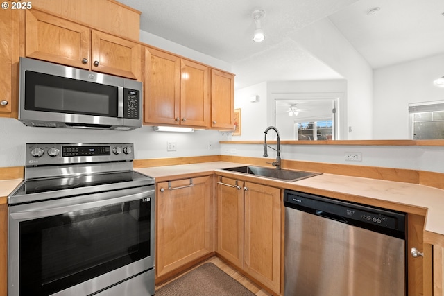 kitchen with a peninsula, stainless steel appliances, a sink, and light countertops