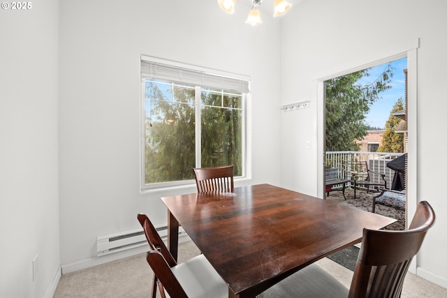 dining space with baseboard heating, light carpet, and a chandelier