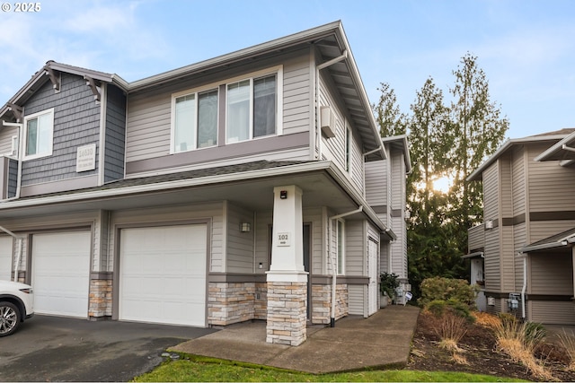 view of front of property with a porch, stone siding, driveway, and an attached garage