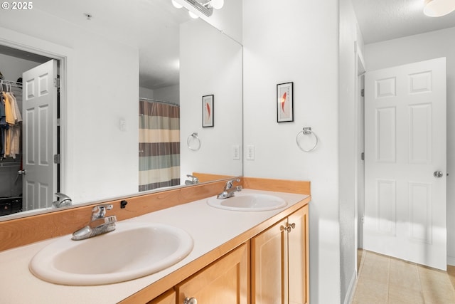 bathroom with tile patterned floors, a sink, a shower with curtain, and double vanity