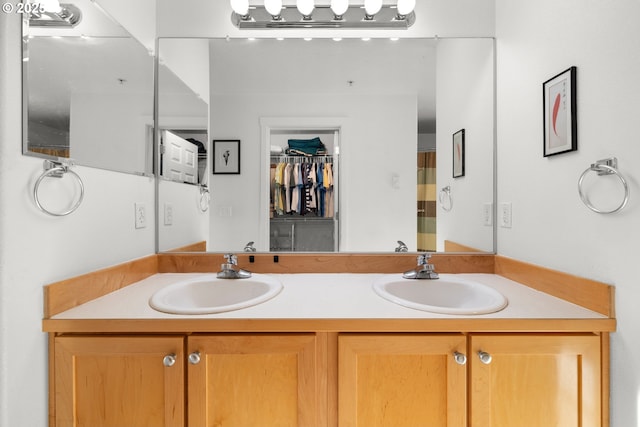 bathroom featuring double vanity, a spacious closet, and a sink