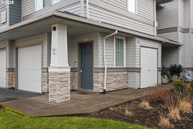 property entrance with a garage and stone siding