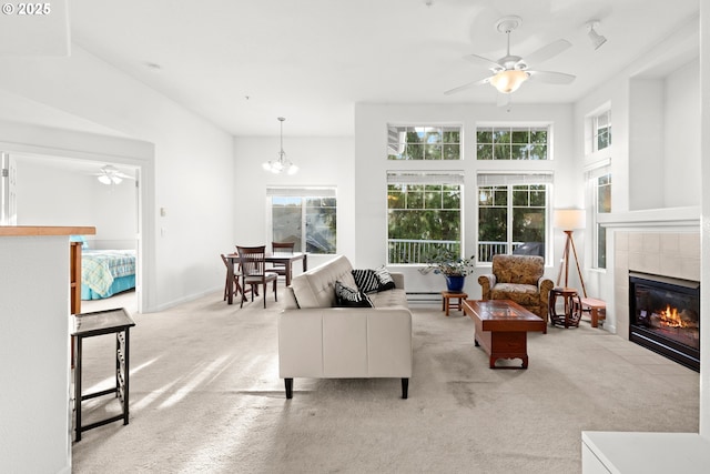 carpeted living room with a fireplace and ceiling fan with notable chandelier