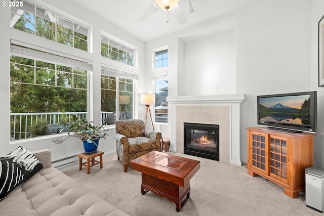 sunroom with a baseboard radiator, ceiling fan, and a tile fireplace