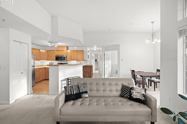 living room featuring an inviting chandelier, baseboards, and light colored carpet