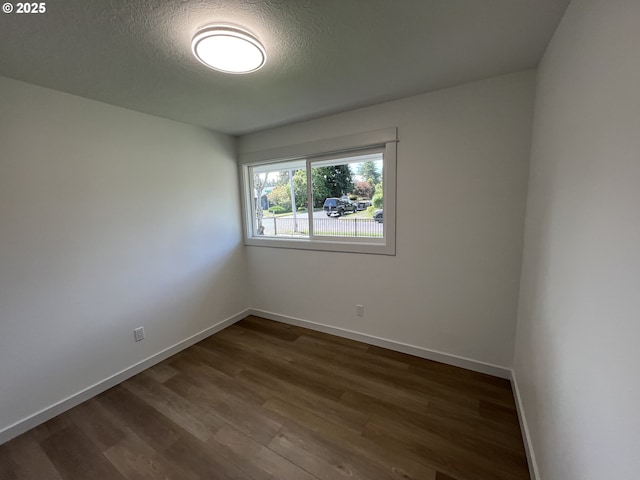 spare room with dark wood finished floors, baseboards, and a textured ceiling