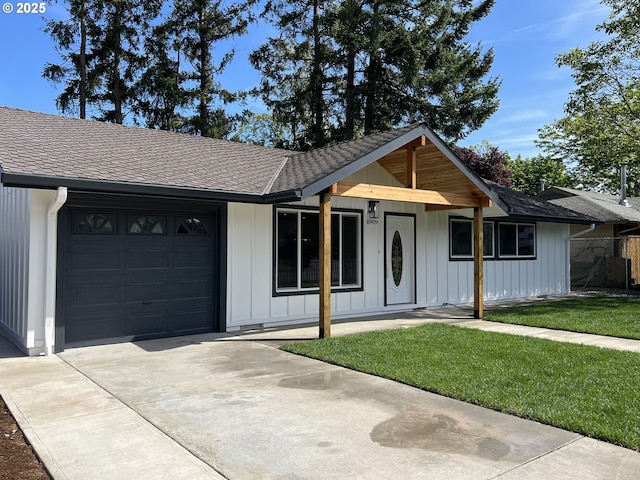 ranch-style home featuring an attached garage, board and batten siding, driveway, roof with shingles, and a front lawn