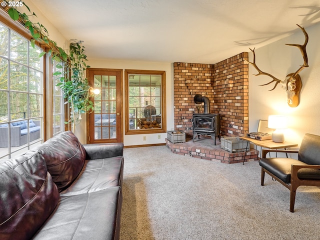 carpeted living area featuring a wood stove and baseboards