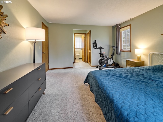 bedroom with light colored carpet, baseboards, and ensuite bathroom