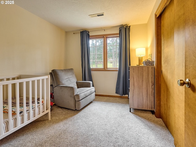 carpeted bedroom featuring a nursery area, visible vents, and a textured ceiling