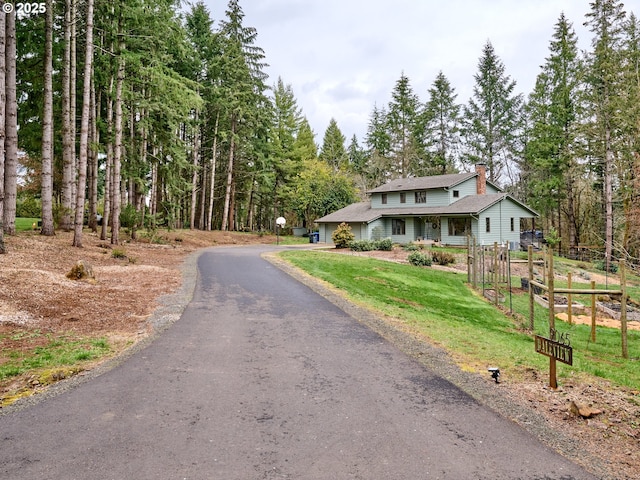 view of front of house featuring driveway, a chimney, and a front lawn