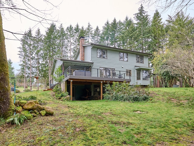 rear view of house featuring a deck, a lawn, and a chimney