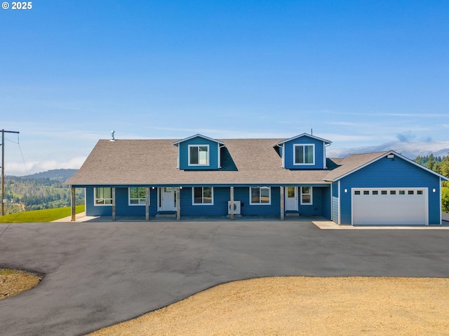 1091 N Echo Mountain Rd, Otis, OR 97368 - view of front facade featuring asphalt driveway, a garage, a mountain view, a porch, and a shingled roof