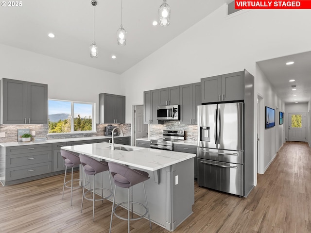 1091 N Echo Mountain Rd, Otis, OR 97368 - kitchen featuring appliances with stainless steel finishes, high vaulted ceiling, gray cabinets, a center island with sink, and decorative backsplash
